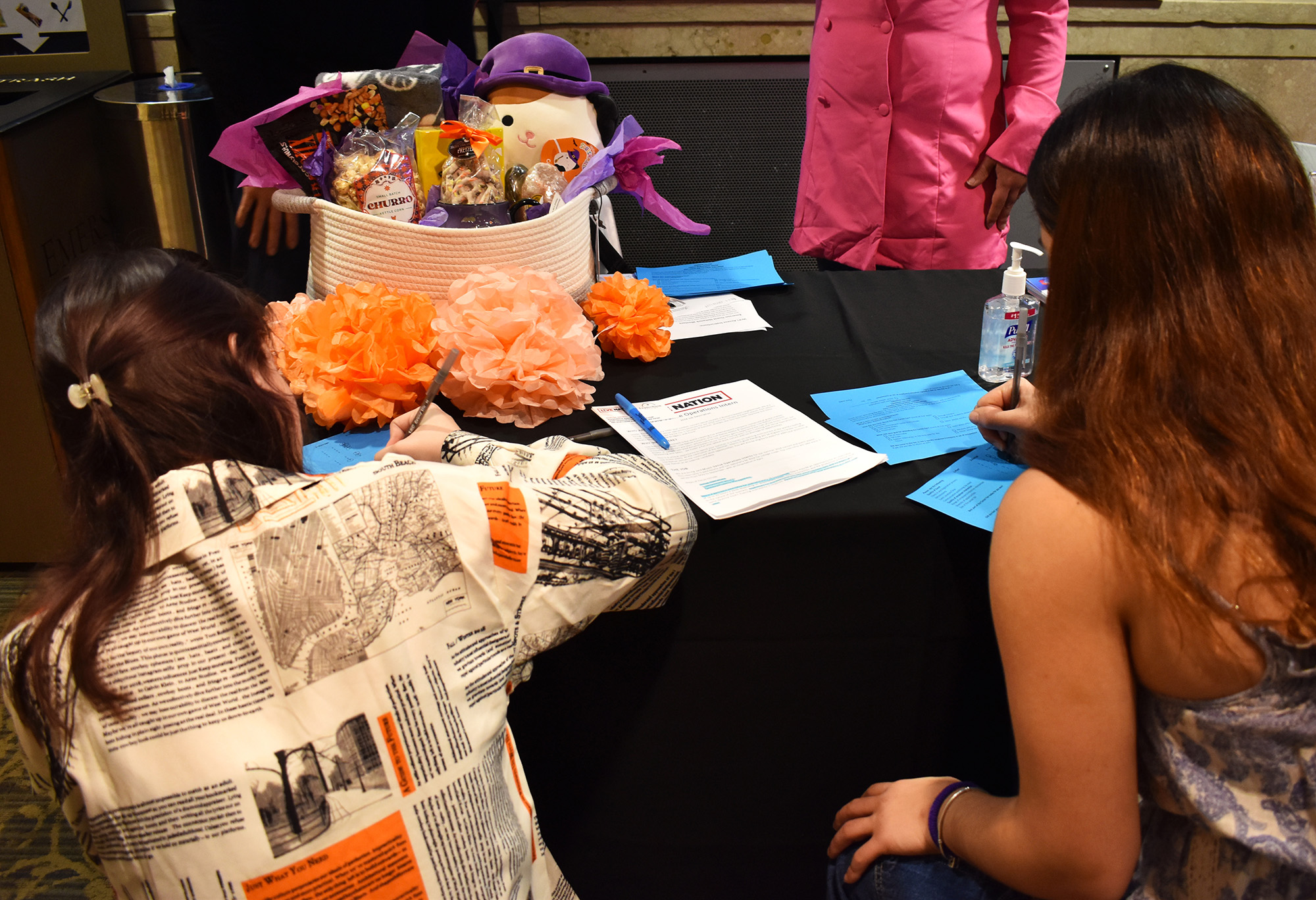 Students fill out surveys on a table with the Career Fair raffle prize and a flyer for one of LiveNation's intern positions